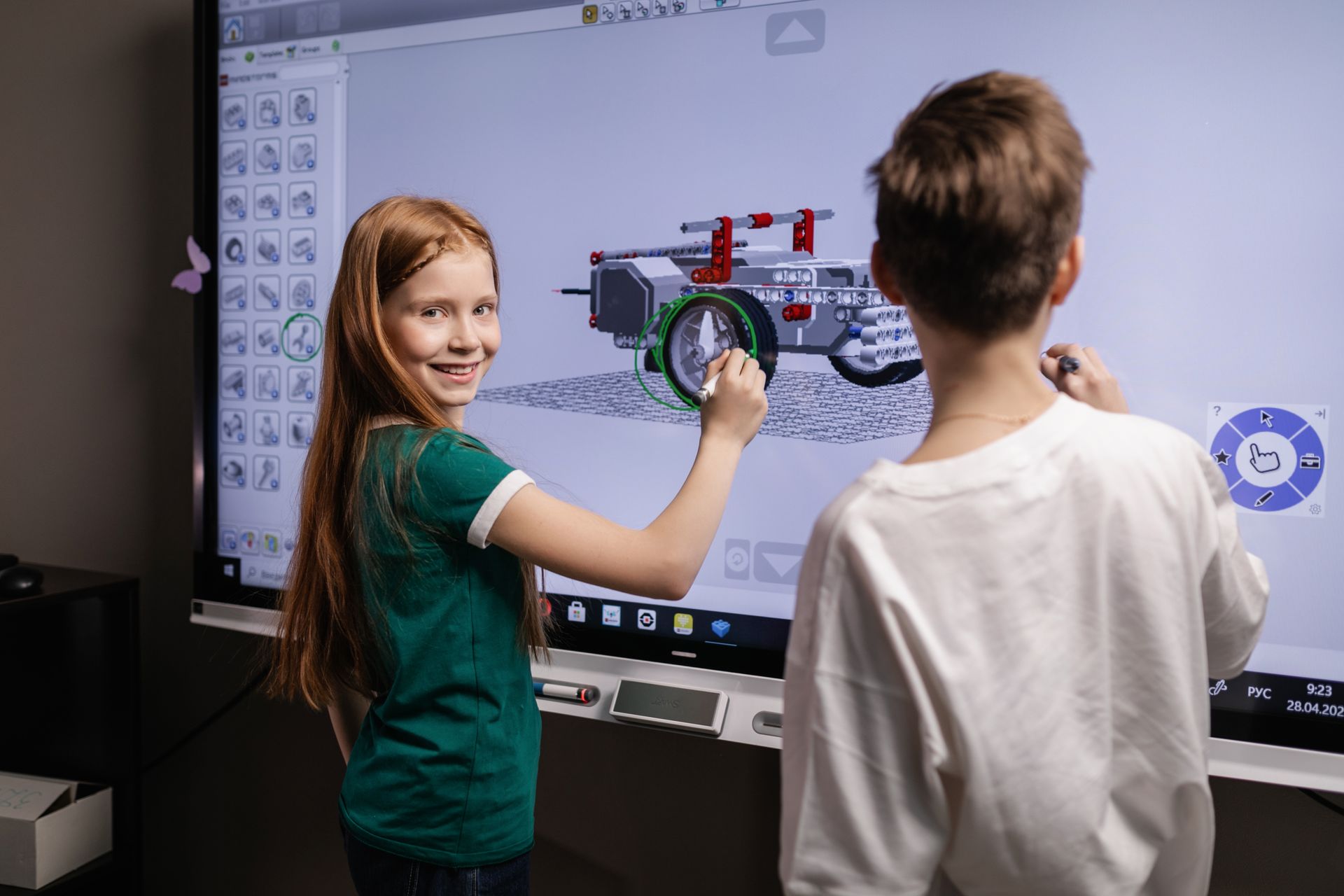 Dve deti spoločne skladajú 3D model na interaktívnej obrazovke